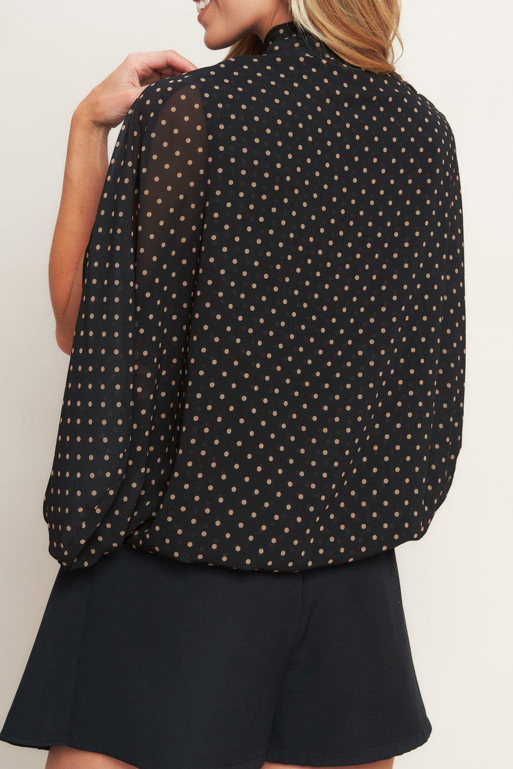 A woven dotted top featuring front bow tie and capelet.