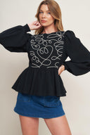 A solid woven top featuring round neckline, long sleeve, embellished bodice, peplum and back zipper closure