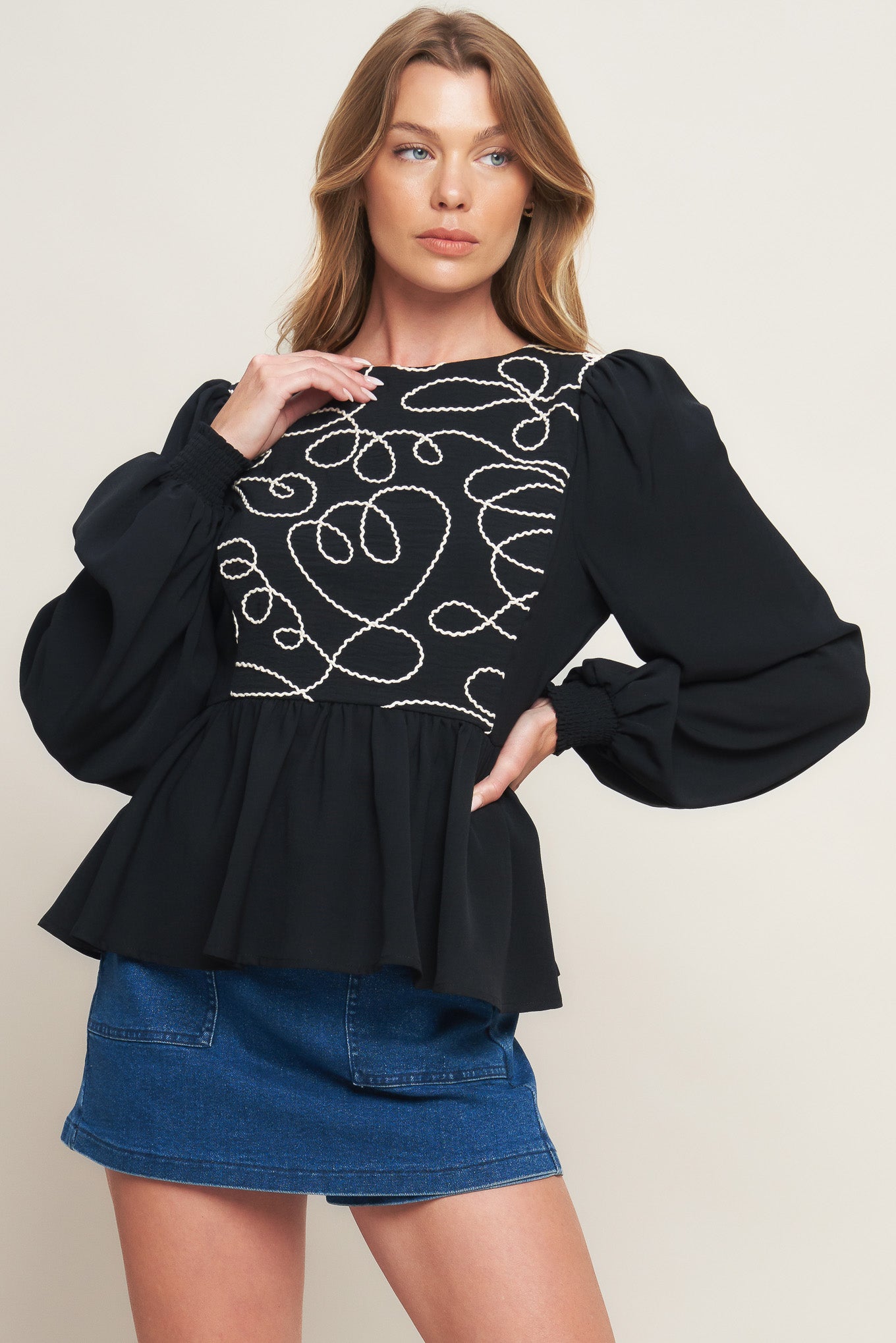 A solid woven top featuring round neckline, long sleeve, embellished bodice, peplum and back zipper closure