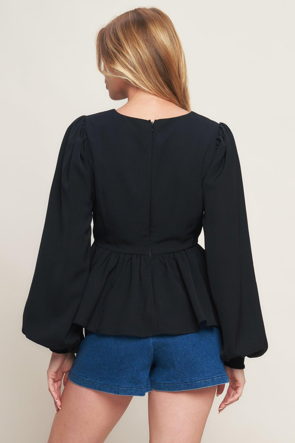 A solid woven top featuring round neckline, long sleeve, embellished bodice, peplum and back zipper closure