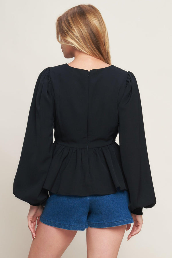 A solid woven top featuring round neckline, long sleeve, embellished bodice, peplum and back zipper closure