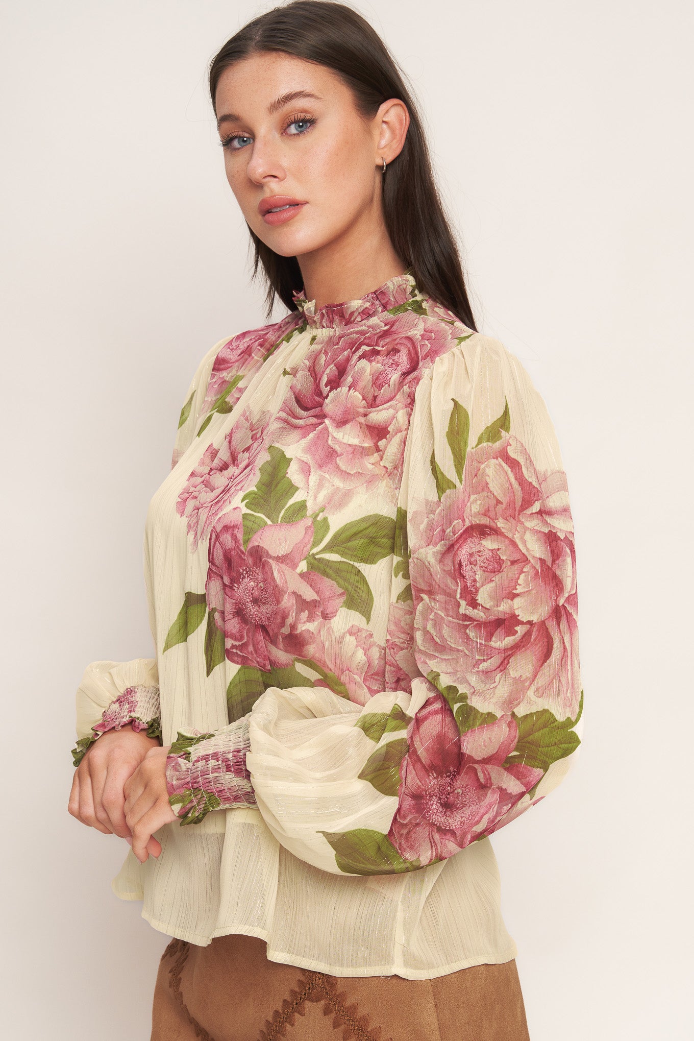 A printed woven top featuring ruffled high neckline, long sleeve with smocked cuff, back neck button closure and cami