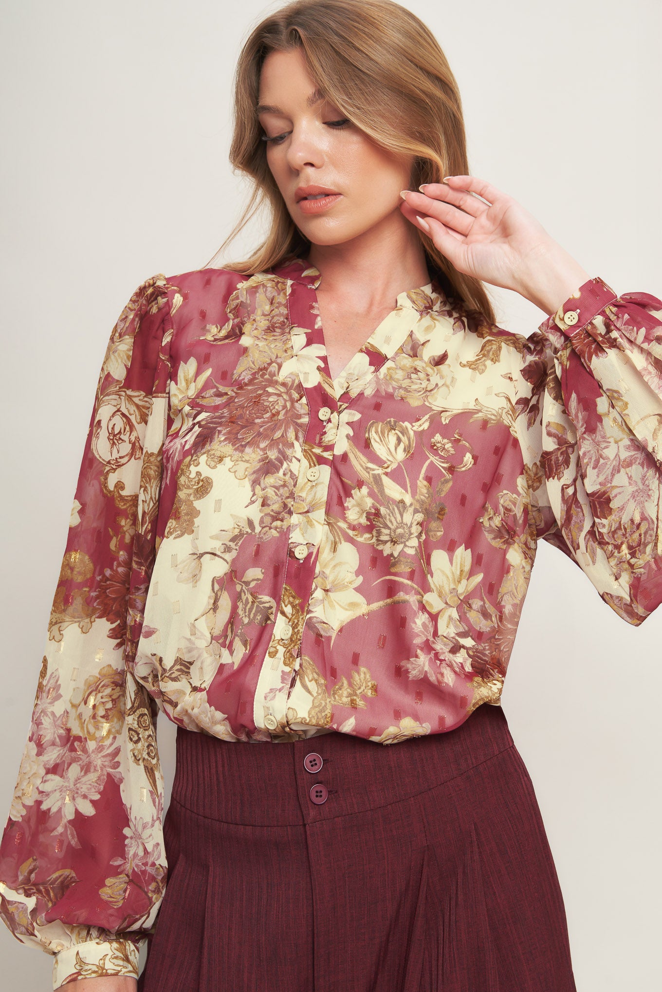A printed woven top featuring round neckline with V front, long sleeve with cuff and button down closure