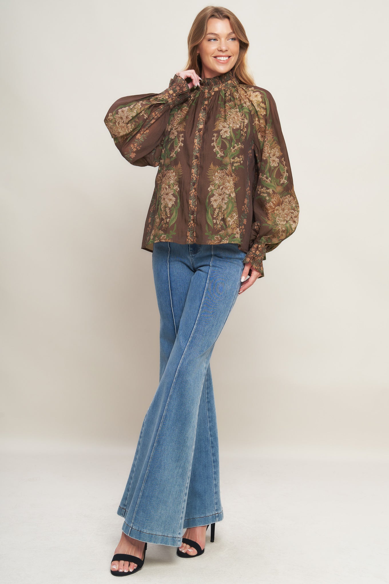 A printed woven top featuring ruffled high neckline, long sleeve with cuff and front button down closure