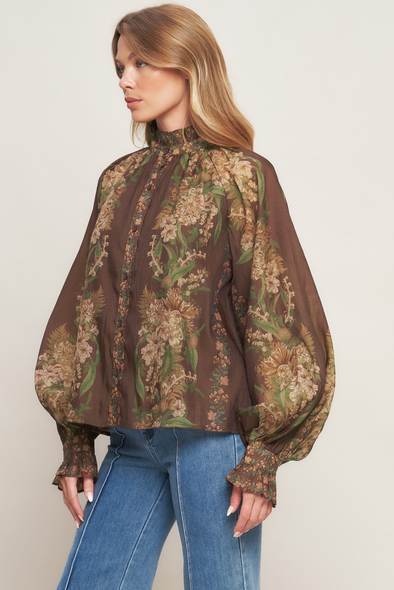 A printed woven top featuring ruffled high neckline, long sleeve with cuff and front button down closure