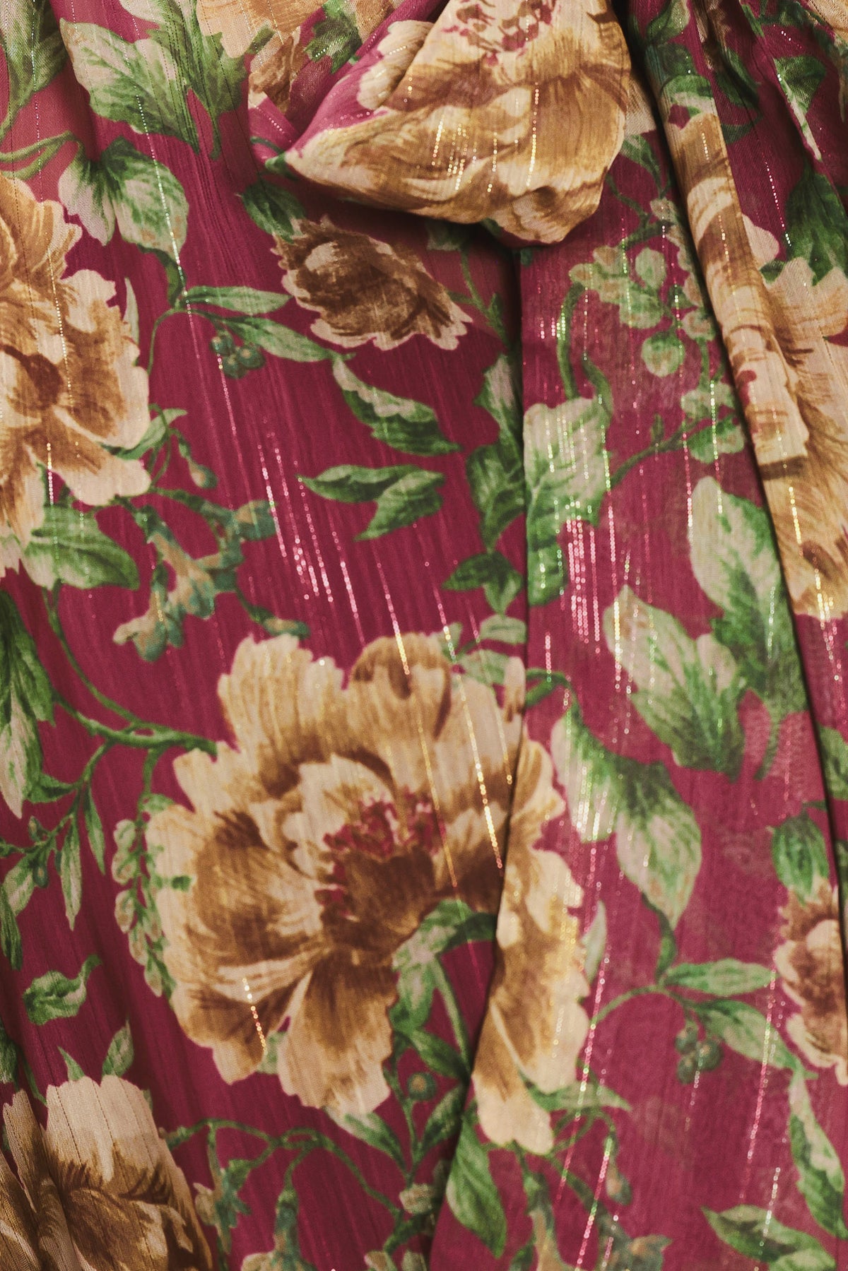 Woman wearing a long sleeve burgundy blouse with floral print and bow tie around the neck | Flying Tomato