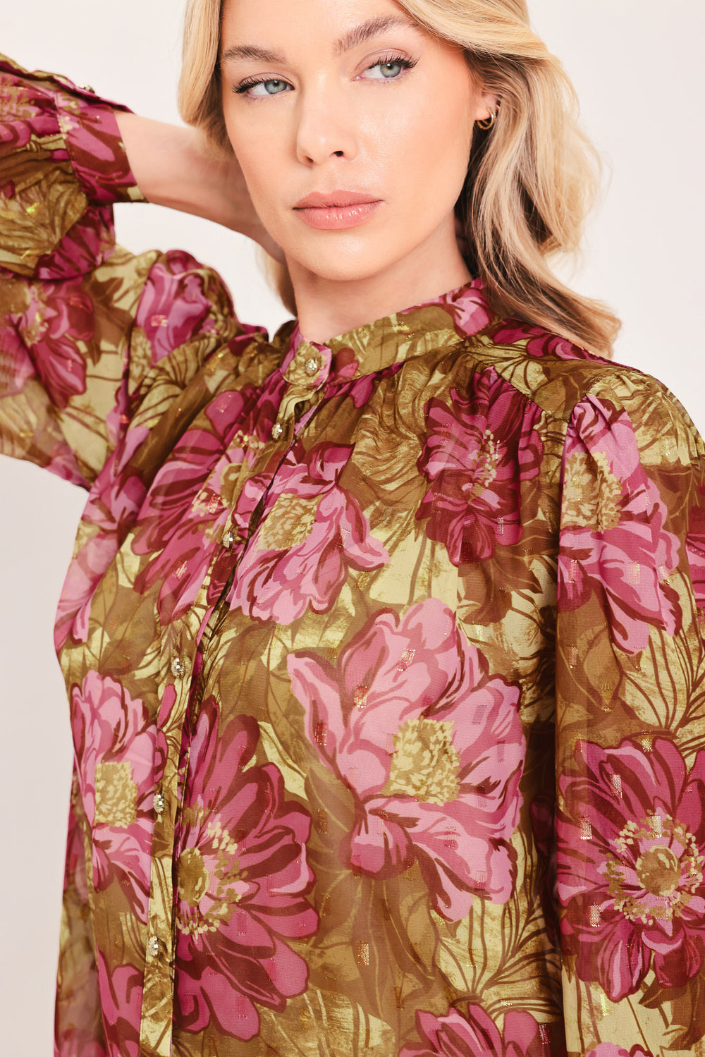 A woman modeling a long-sleeve high-neck blouse with a dense floral pattern in olive green, pink, and burgundy | Flying Tomato