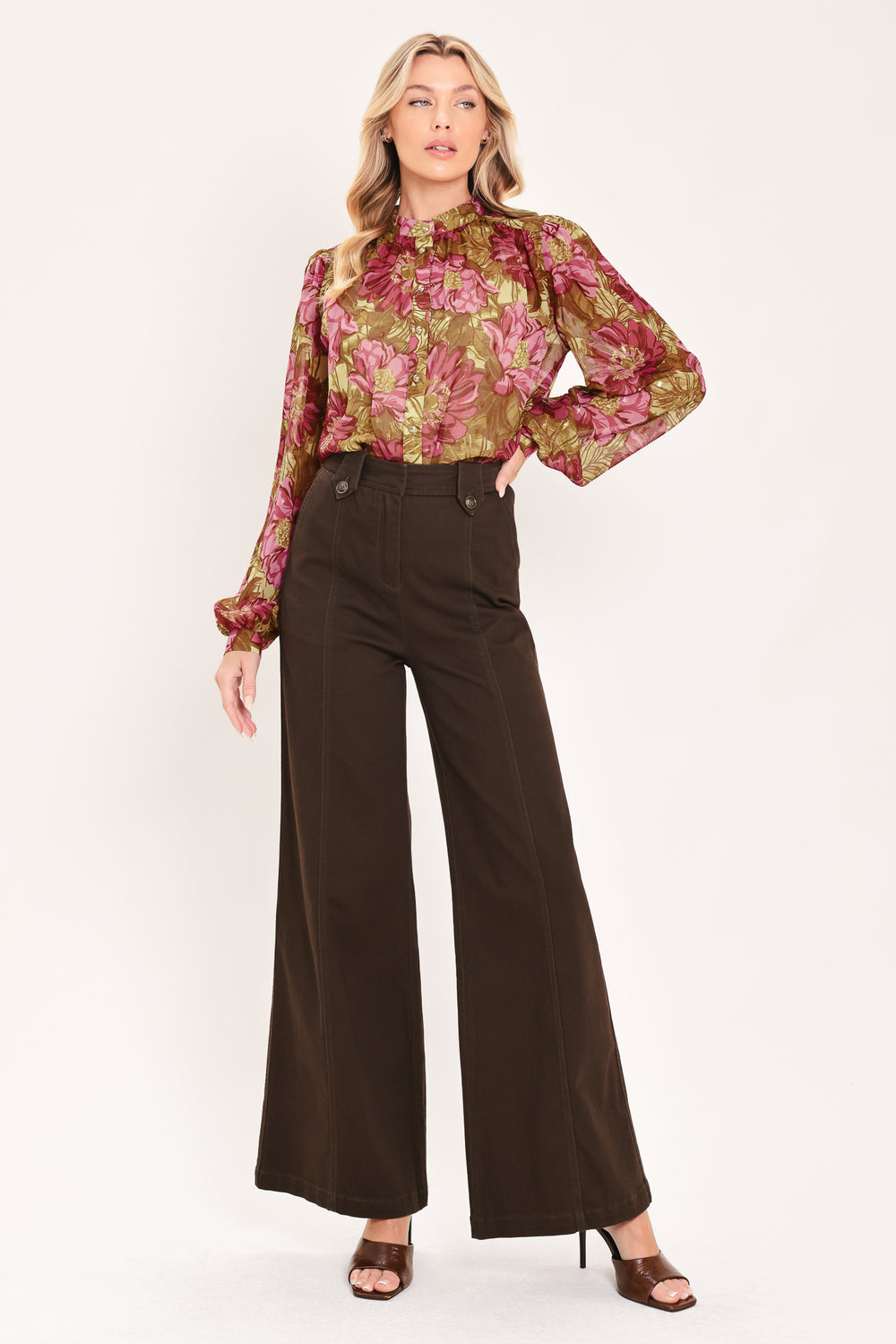 A woman modeling a long-sleeve high-neck blouse with a dense floral pattern in olive green, pink, and burgundy | Flying Tomato