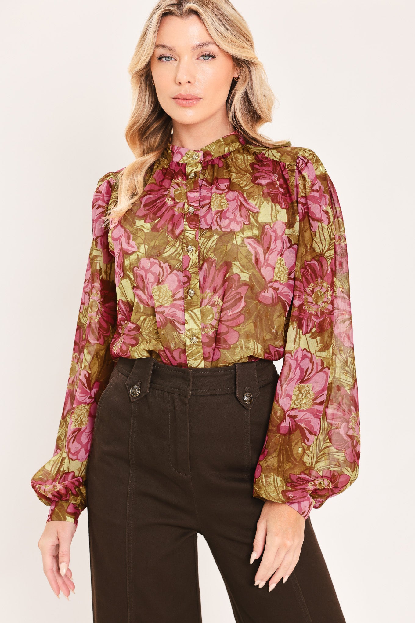 A woman modeling a long-sleeve high-neck blouse with a dense floral pattern in olive green, pink, and burgundy | Flying Tomato
