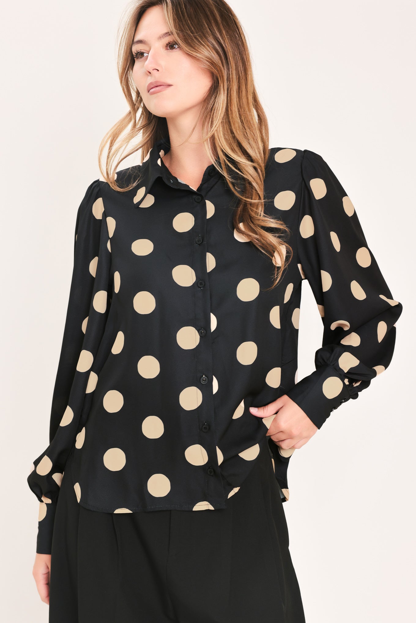 A woman wearing a polka dot printed woven top featuring collar, long sleeve with button down closure | Flying Tomato