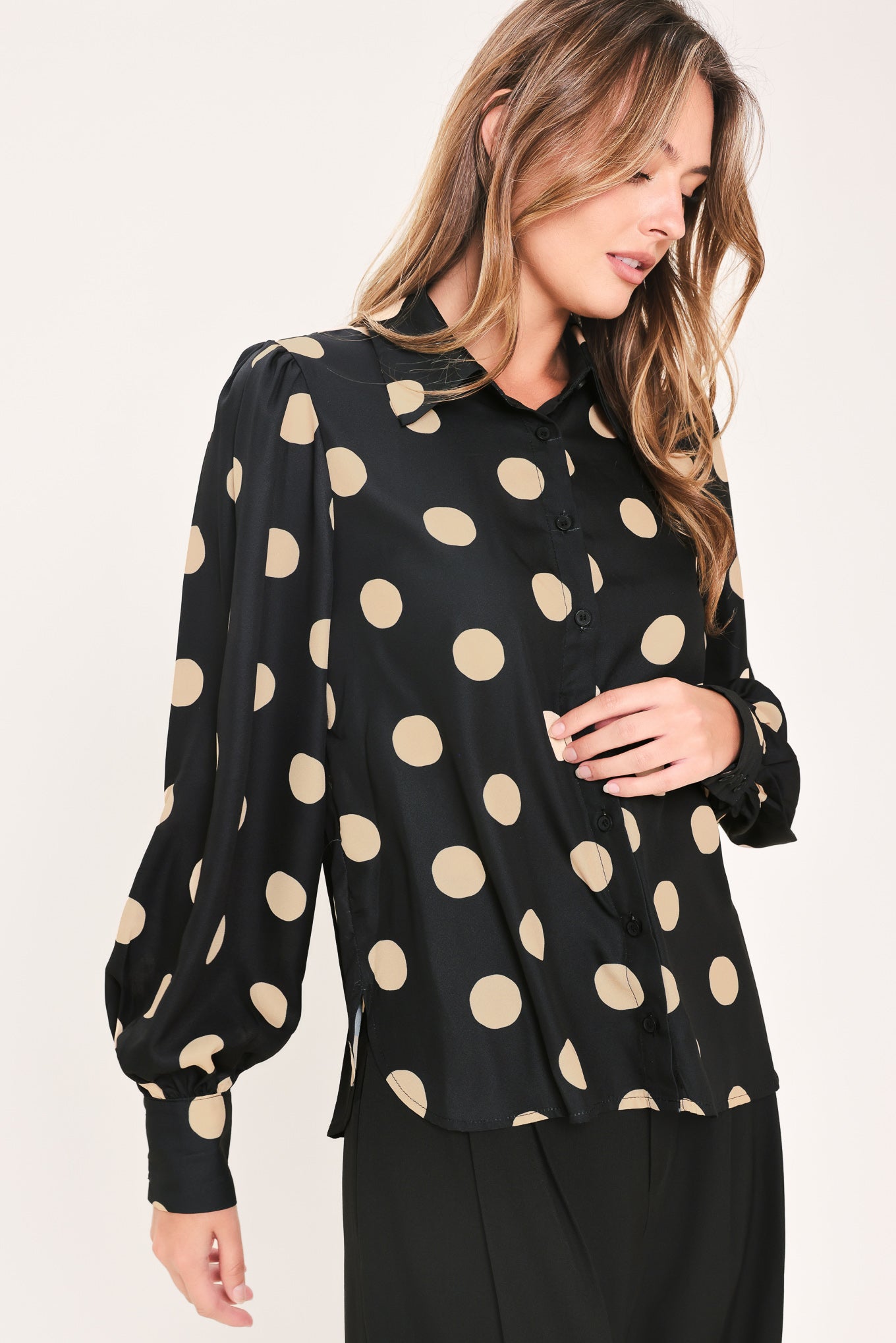 A woman wearing a polka dot printed woven top featuring collar, long sleeve with button down closure | Flying Tomato