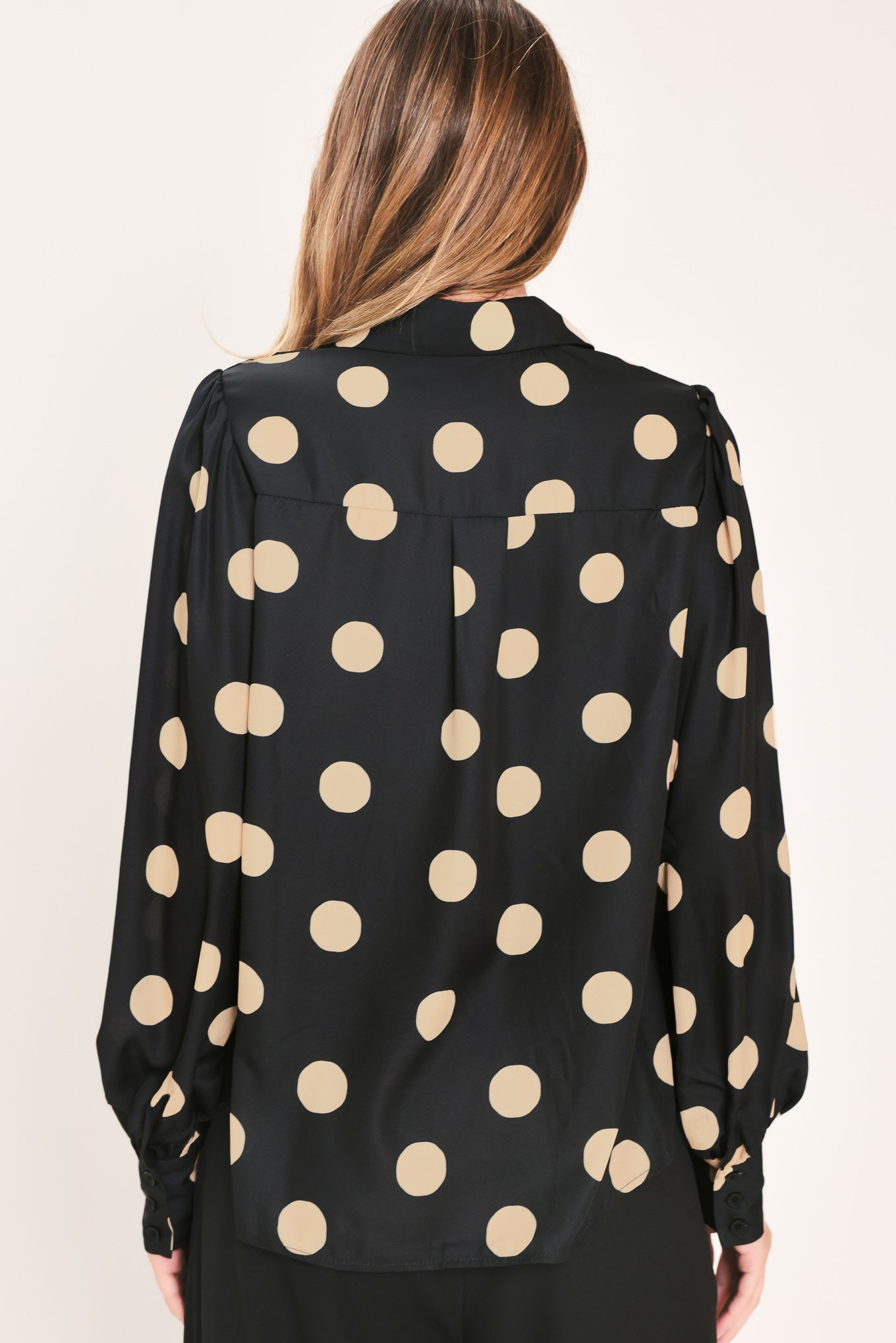 A woman wearing a polka dot printed woven top featuring collar, long sleeve with button down closure | Flying Tomato