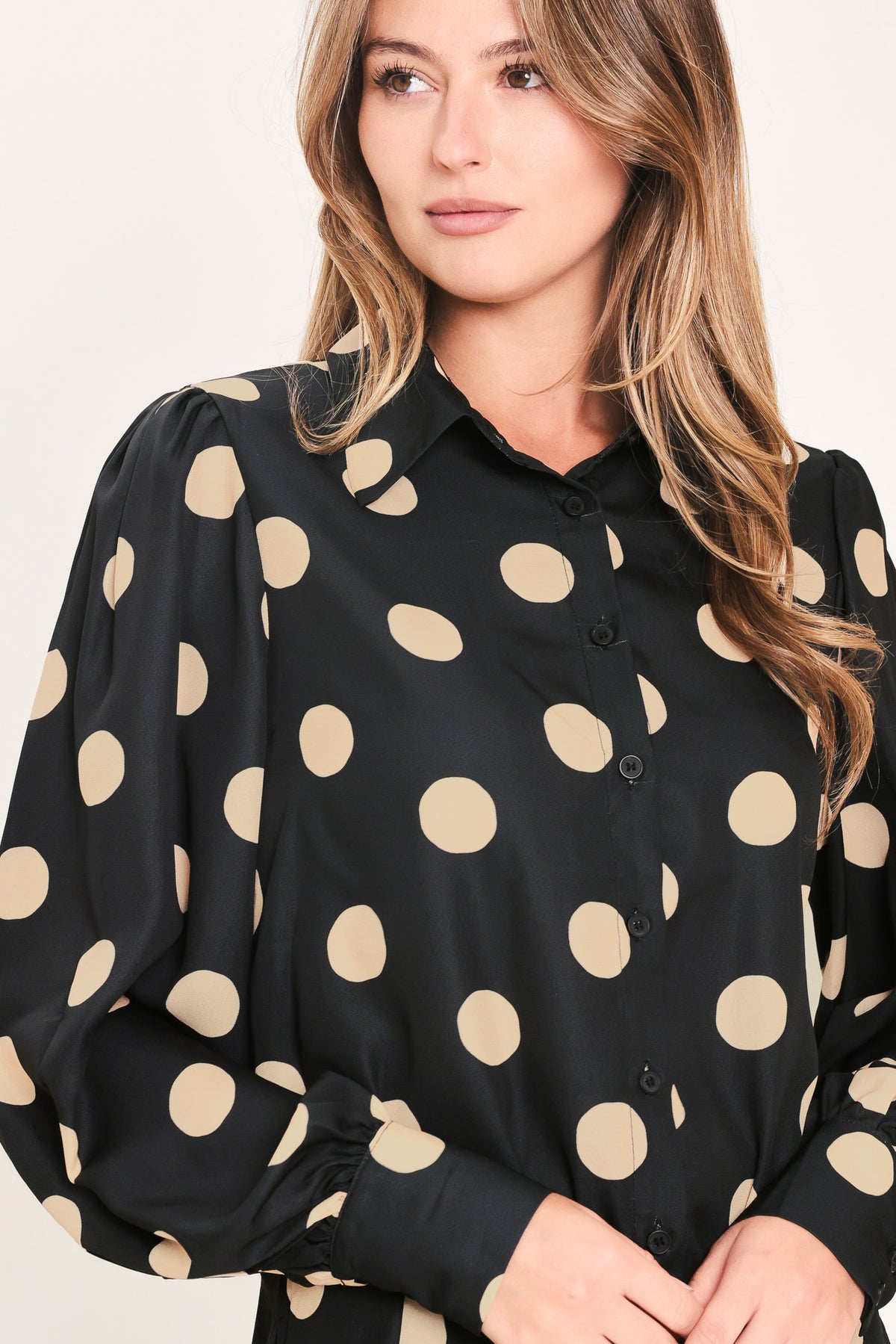 A woman wearing a polka dot printed woven top featuring collar, long sleeve with button down closure | Flying Tomato