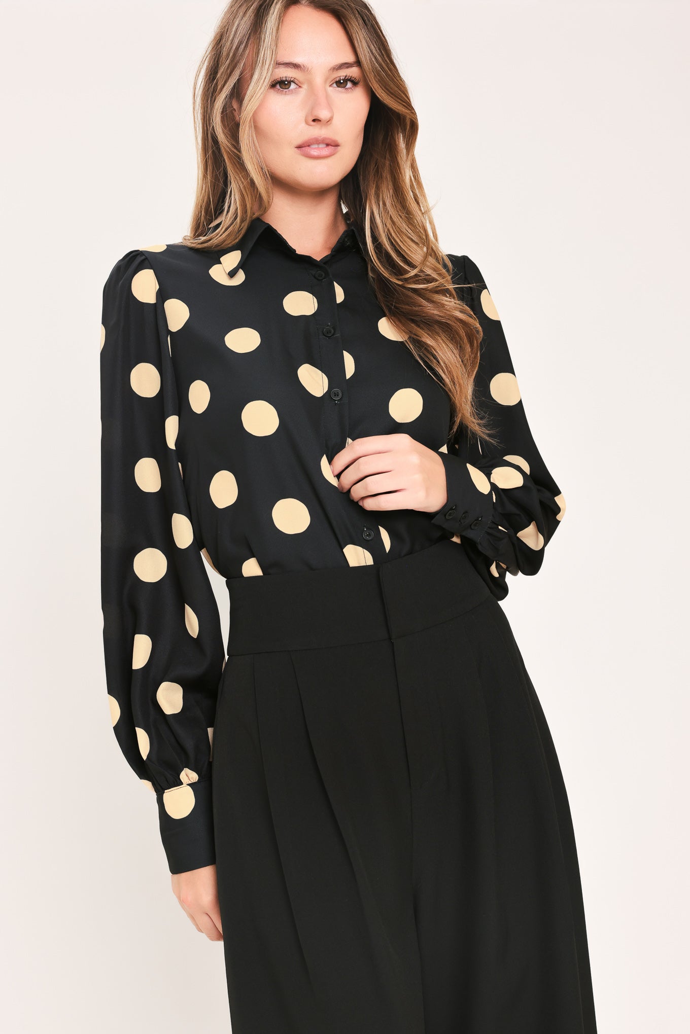 A woman wearing a polka dot printed woven top featuring collar, long sleeve with button down closure | Flying Tomato