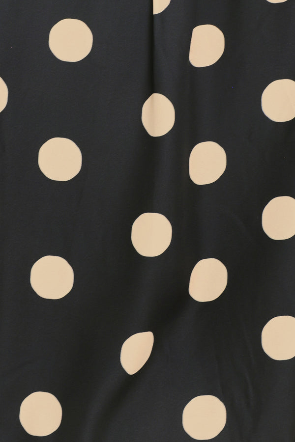 A woman wearing a polka dot printed woven top featuring collar, long sleeve with button down closure | Flying Tomato
