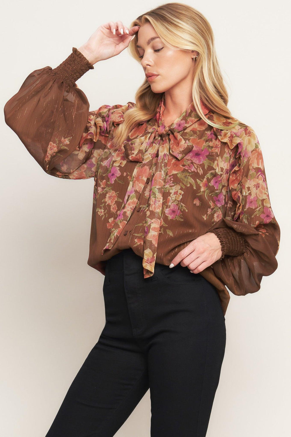 A printed woven top featuring front bow tie, long sleeve with smocked cuff and front button down closure