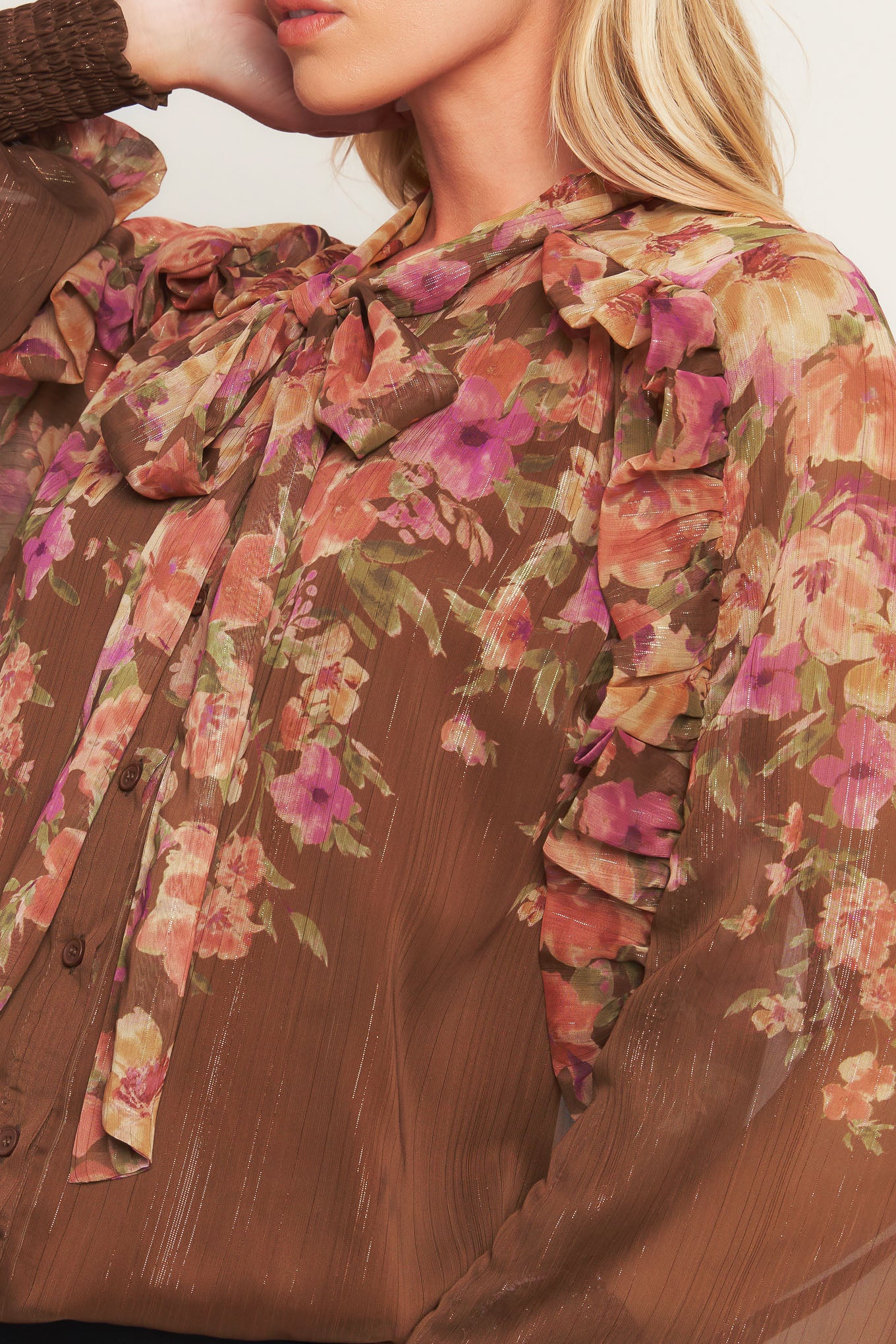 A printed woven top featuring front bow tie, long sleeve with smocked cuff and front button down closure