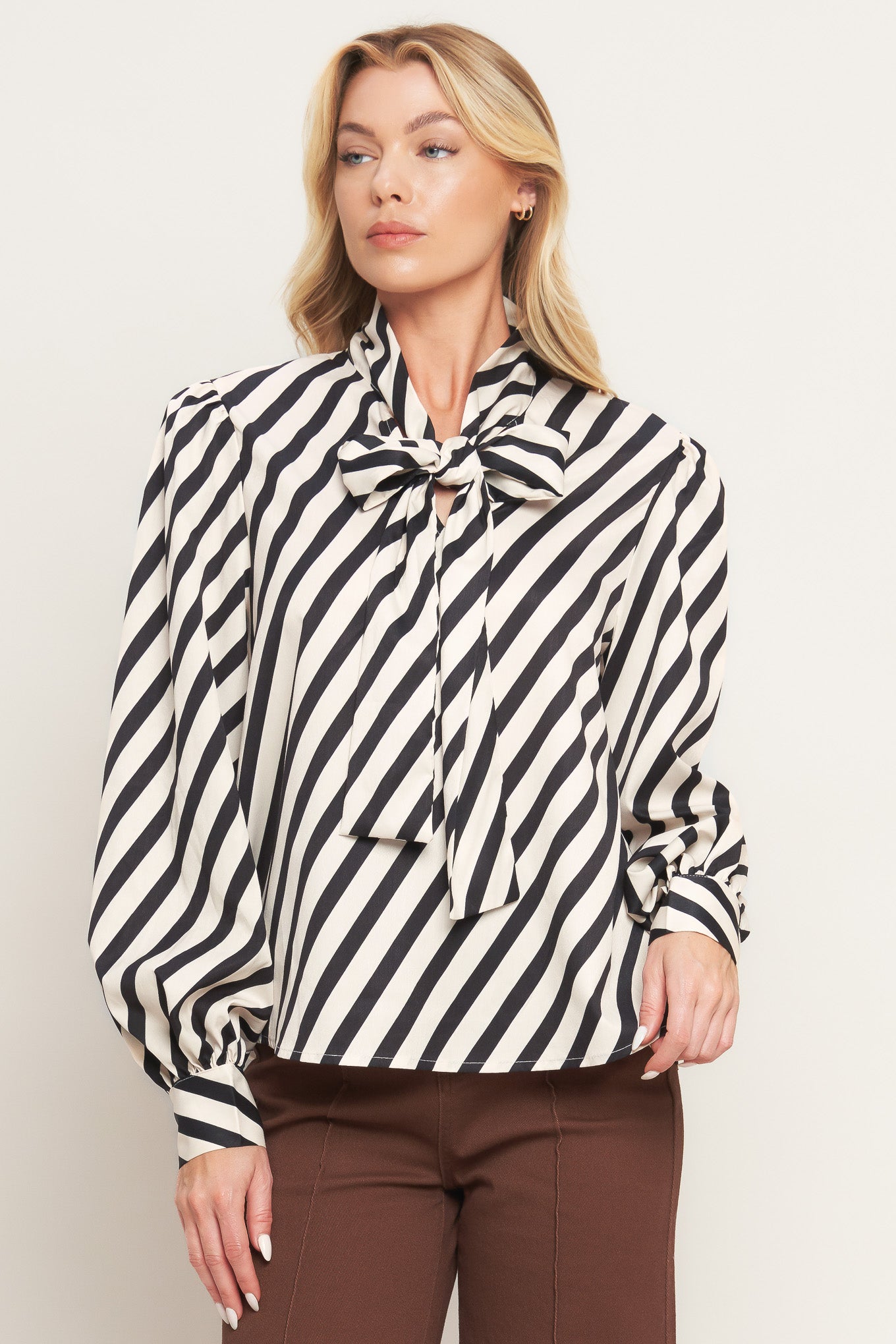 A striped woven top featuring high neckline with front bow tie and long sleeve with cuff