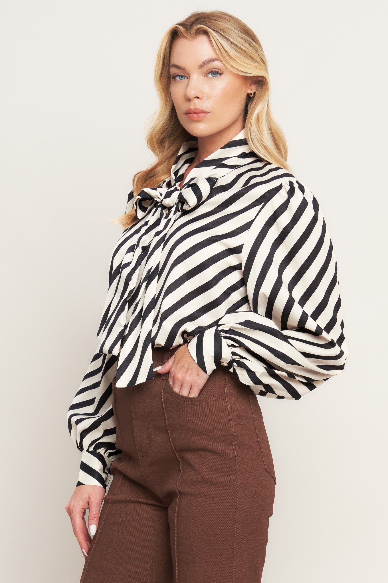 A striped woven top featuring high neckline with front bow tie and long sleeve with cuff