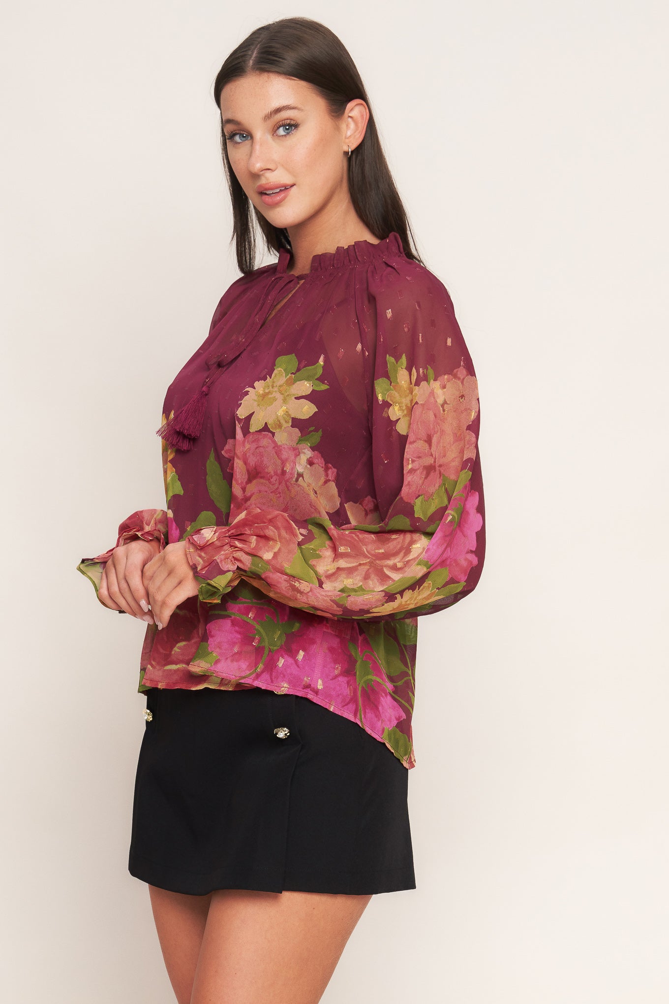 A printed textured woven top featuring ruffled round neckline with front tie, long sleeve with ruffled cuff and cami