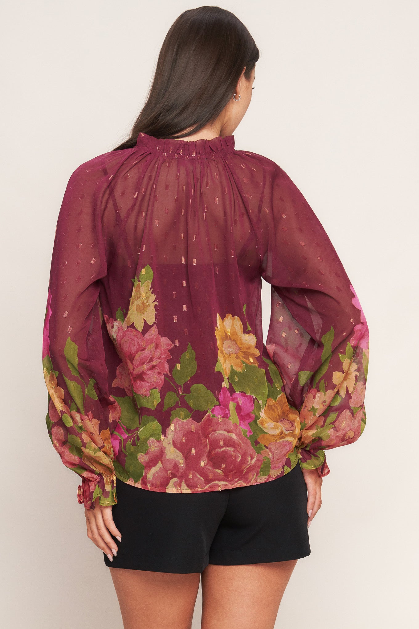 A printed textured woven top featuring ruffled round neckline with front tie, long sleeve with ruffled cuff and cami