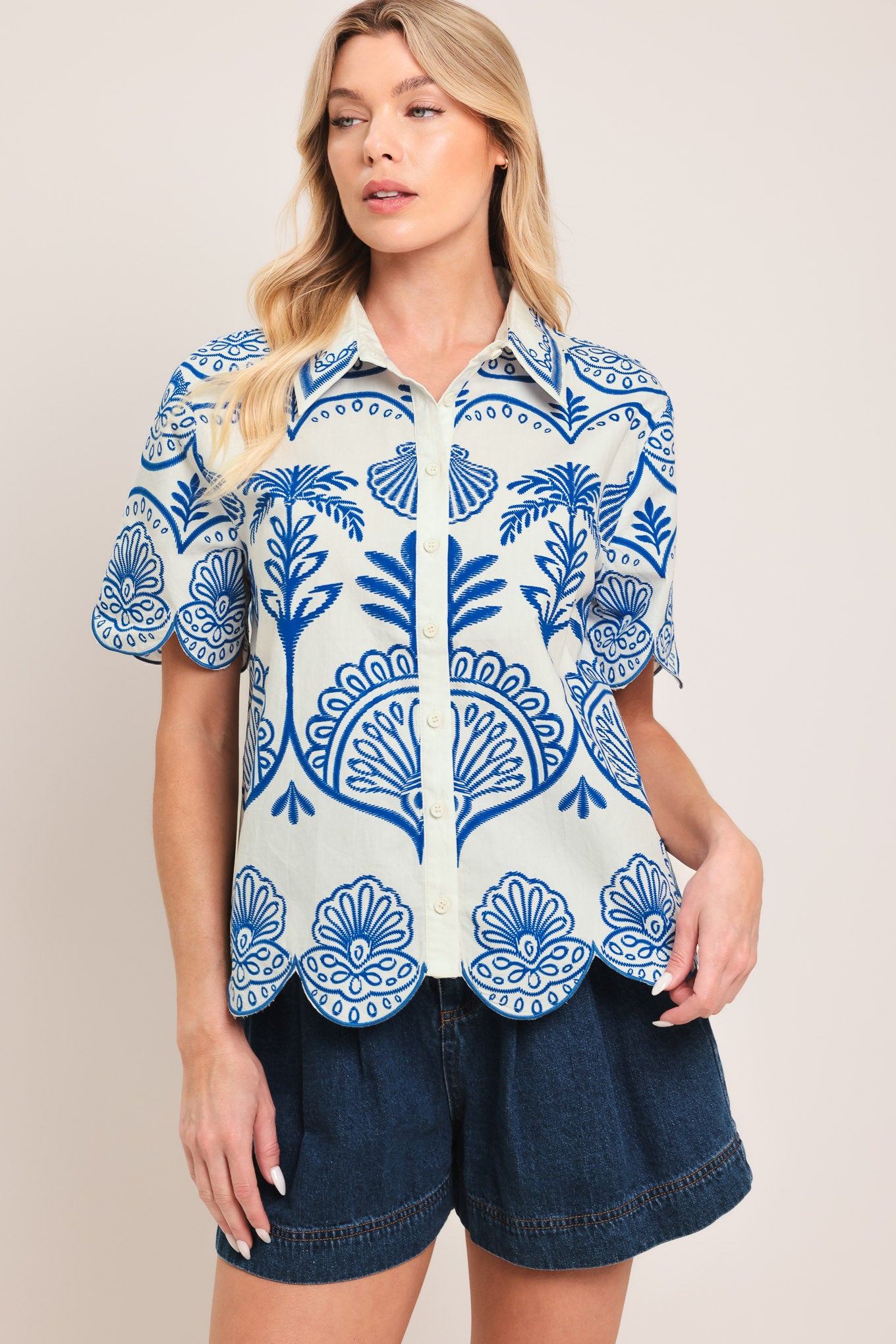 Woman wearing a short sleeve blue and white patterned shirt top with front scallop hem | Flying Tomato