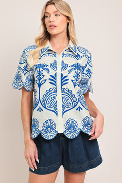 Woman wearing a short sleeve blue and white patterned shirt top with front scallop hem | Flying Tomato