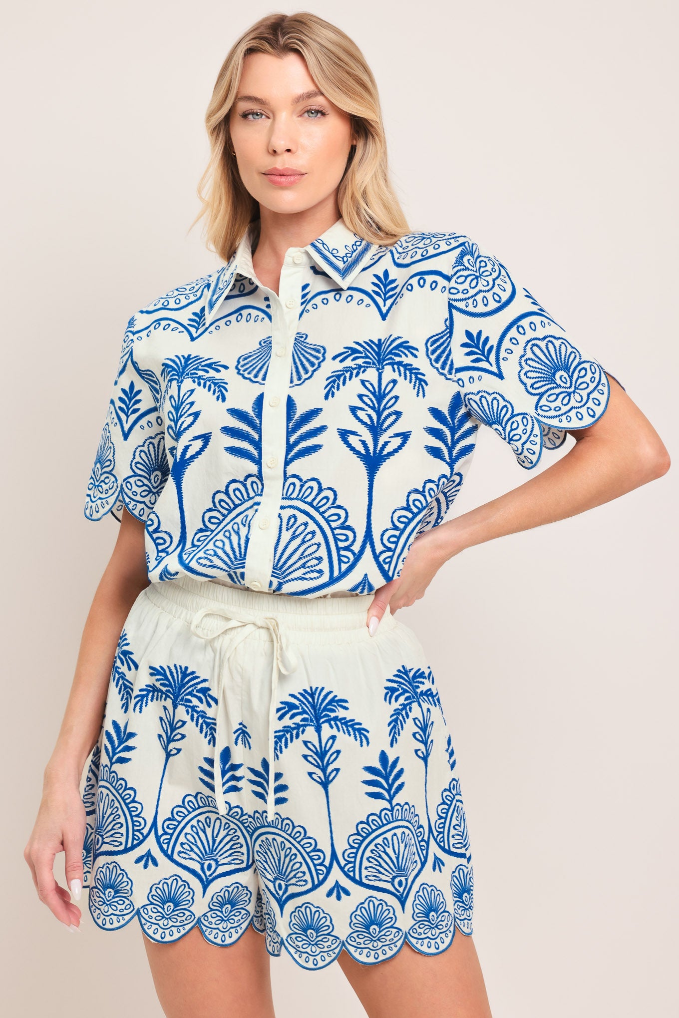 Woman wearing a short sleeve blue and white patterned shirt top with front scallop hem | Flying Tomato