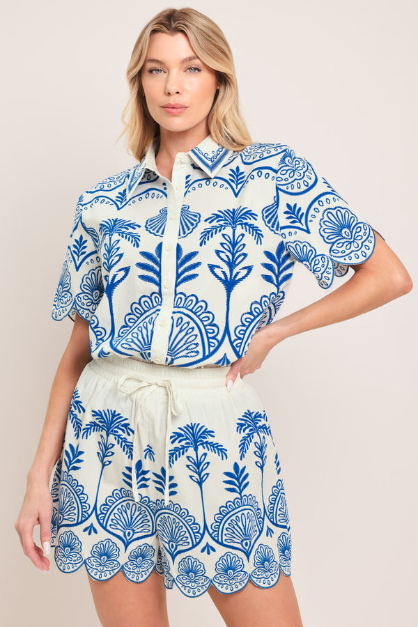 Woman wearing a short sleeve blue and white patterned shirt top with front scallop hem | Flying Tomato