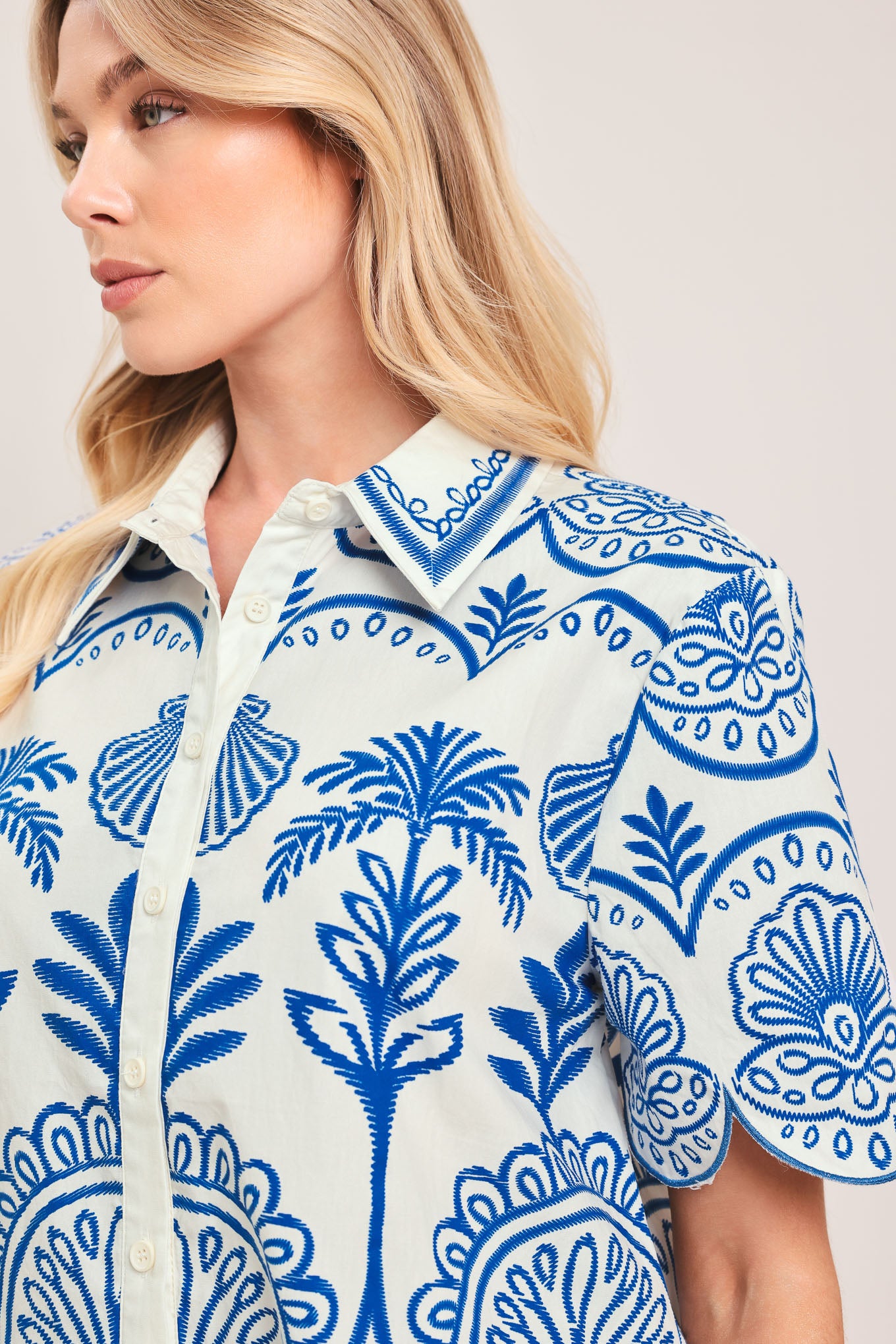 Woman wearing a short sleeve blue and white patterned shirt top with front scallop hem | Flying Tomato