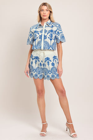 Woman wearing a short sleeve blue and white patterned shirt top with front scallop hem | Flying Tomato