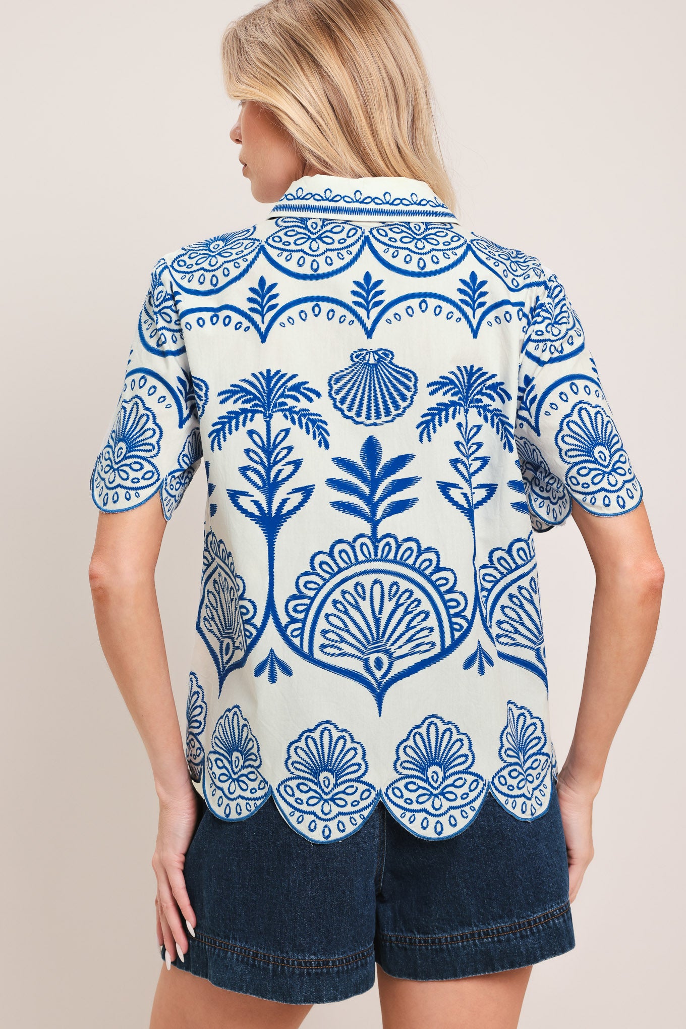 Woman wearing a short sleeve blue and white patterned shirt top with front scallop hem | Flying Tomato