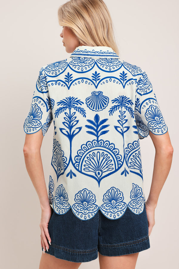 Woman wearing a short sleeve blue and white patterned shirt top with front scallop hem | Flying Tomato