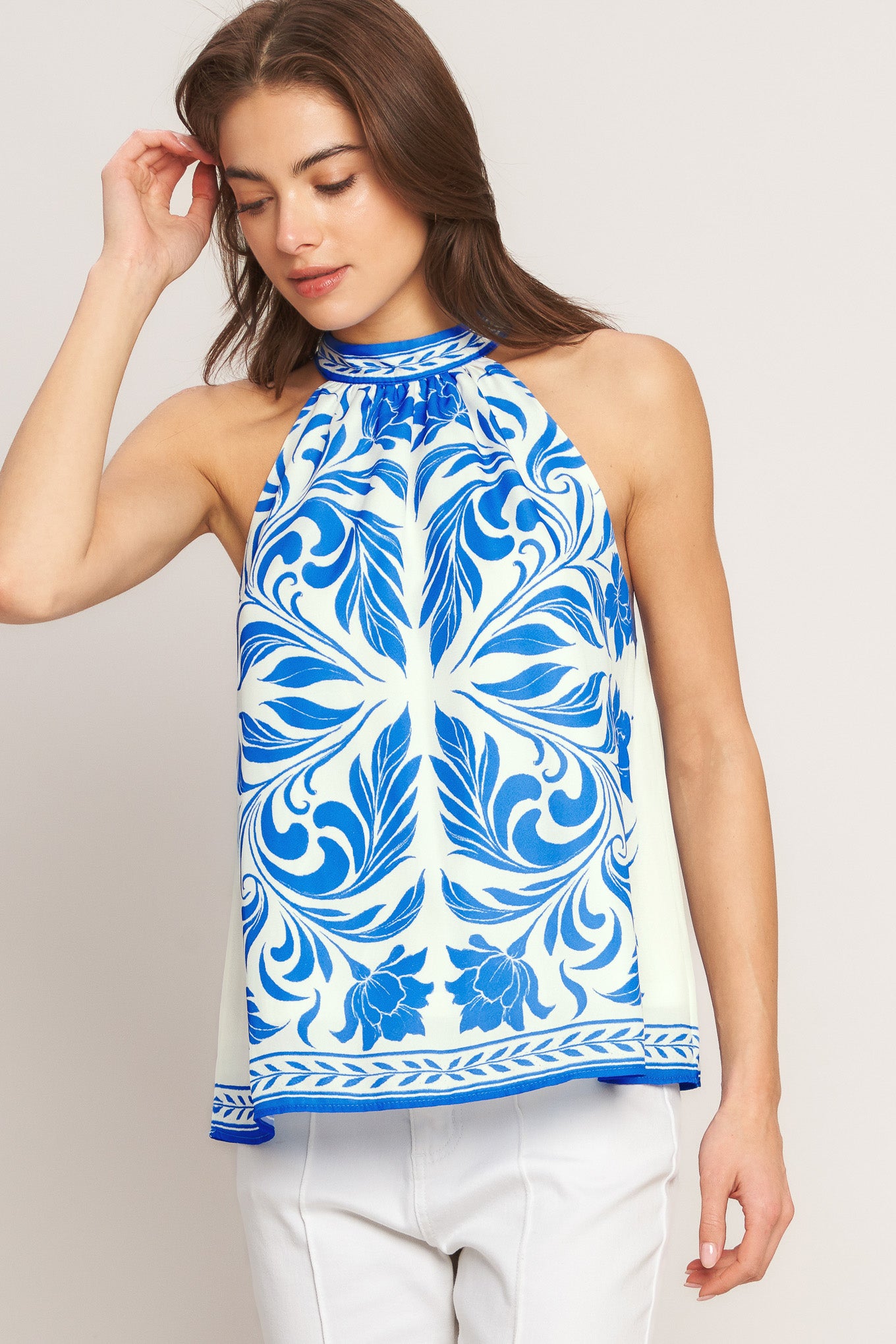 Woman wearing a blue and white patterned sleeveless top on a plain background