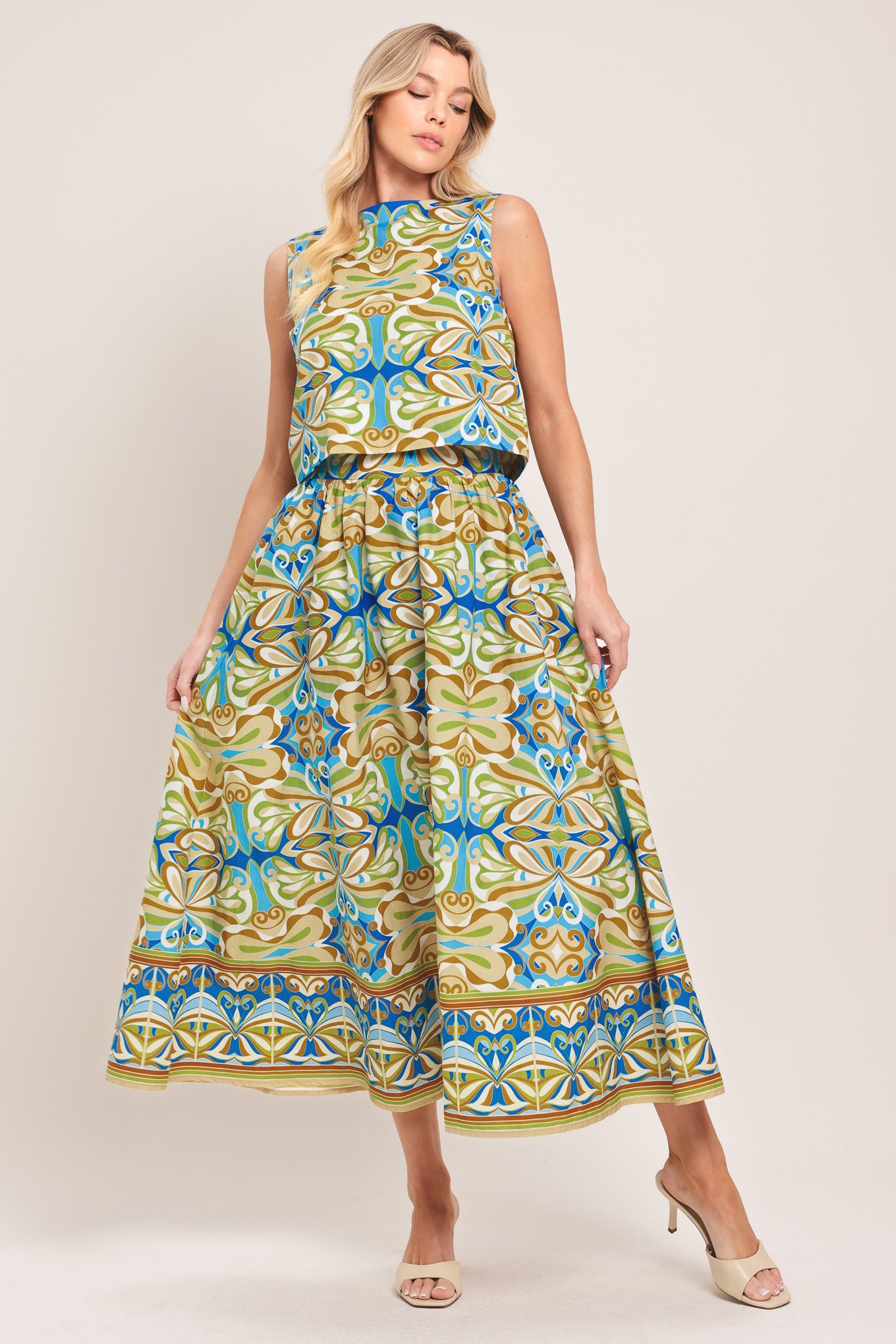 Woman wearing a sleeveless top and skirt with a colorful pattern featuring a round neckline and back button closure | Flying Tomato