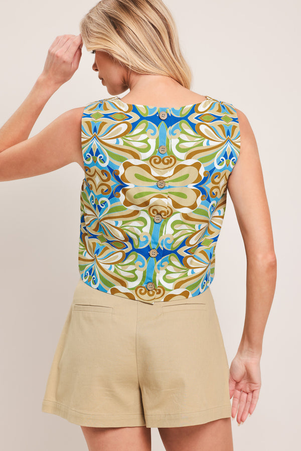 Woman wearing a sleeveless top with a colorful pattern featuring a round neckline and back button closure | Flying Tomato