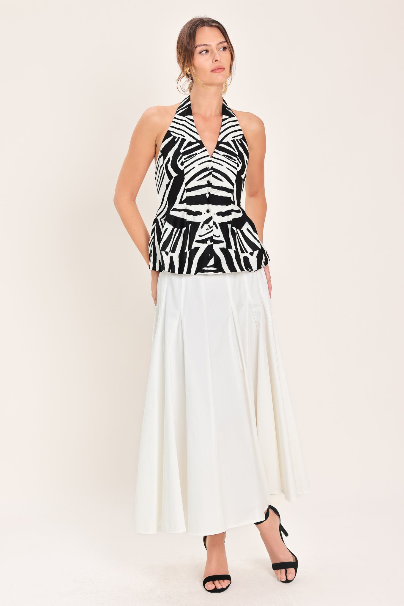 Woman wearing a black and white printed woven halter top with front button down closure | Flying Tomato