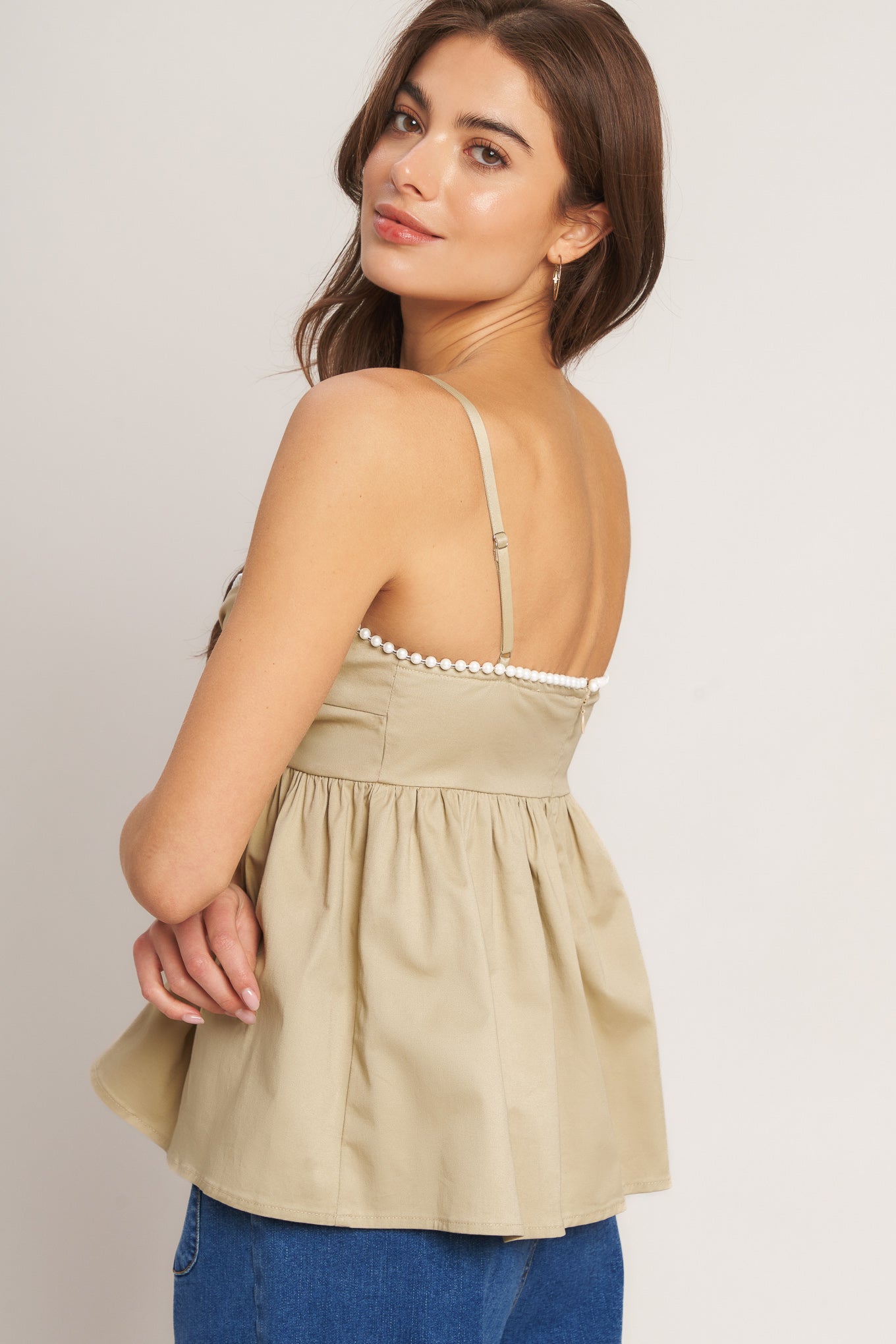 A taupe solid woven top featuring twisted bodice with bead trim, straps and back zipper closure