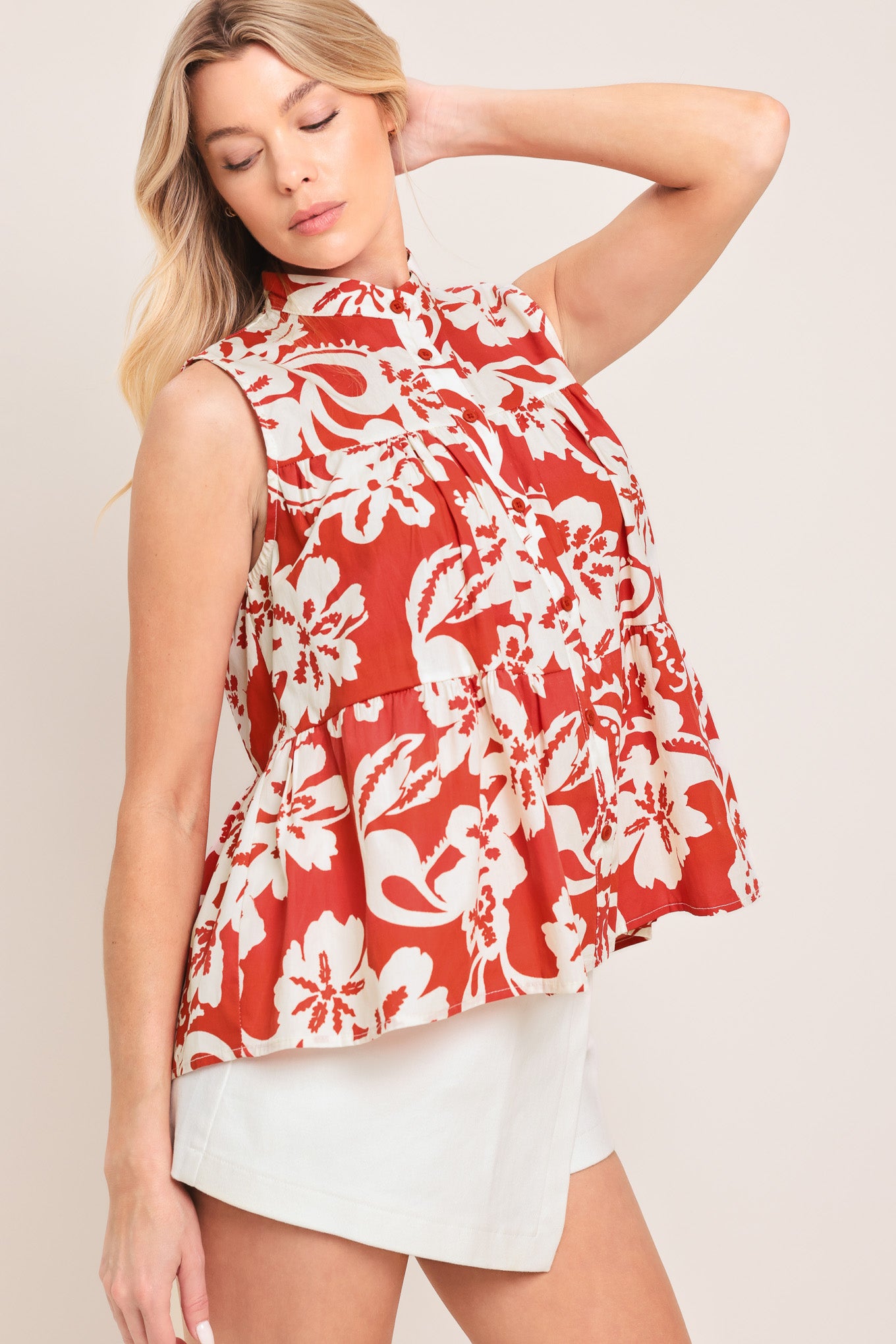 Woman wearing a red and white floral sleeveless top with tiers and front button closure | Flying Tomato