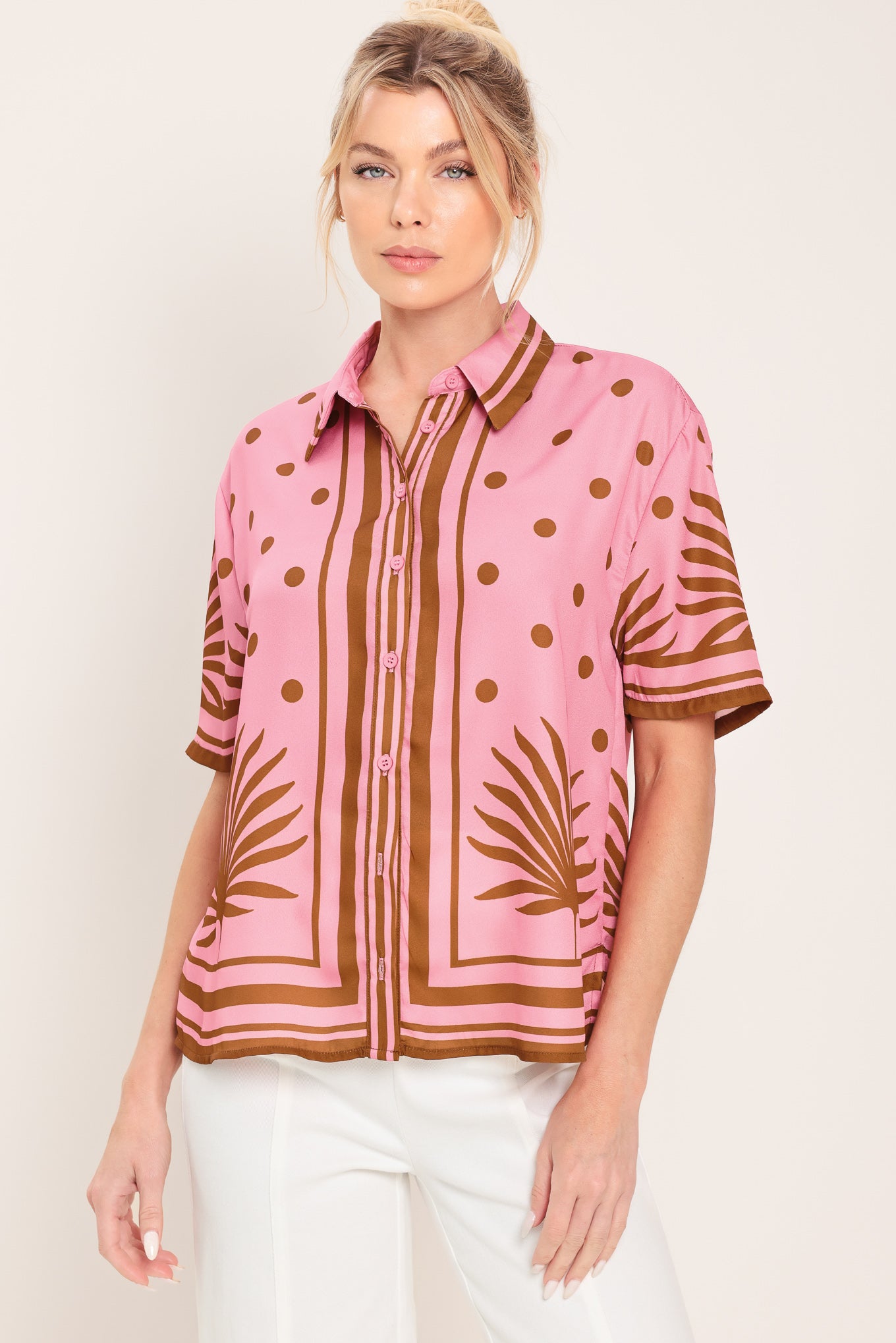 Woman wearing a pink button up top with brown polka dots and printed palms | Flying Tomato