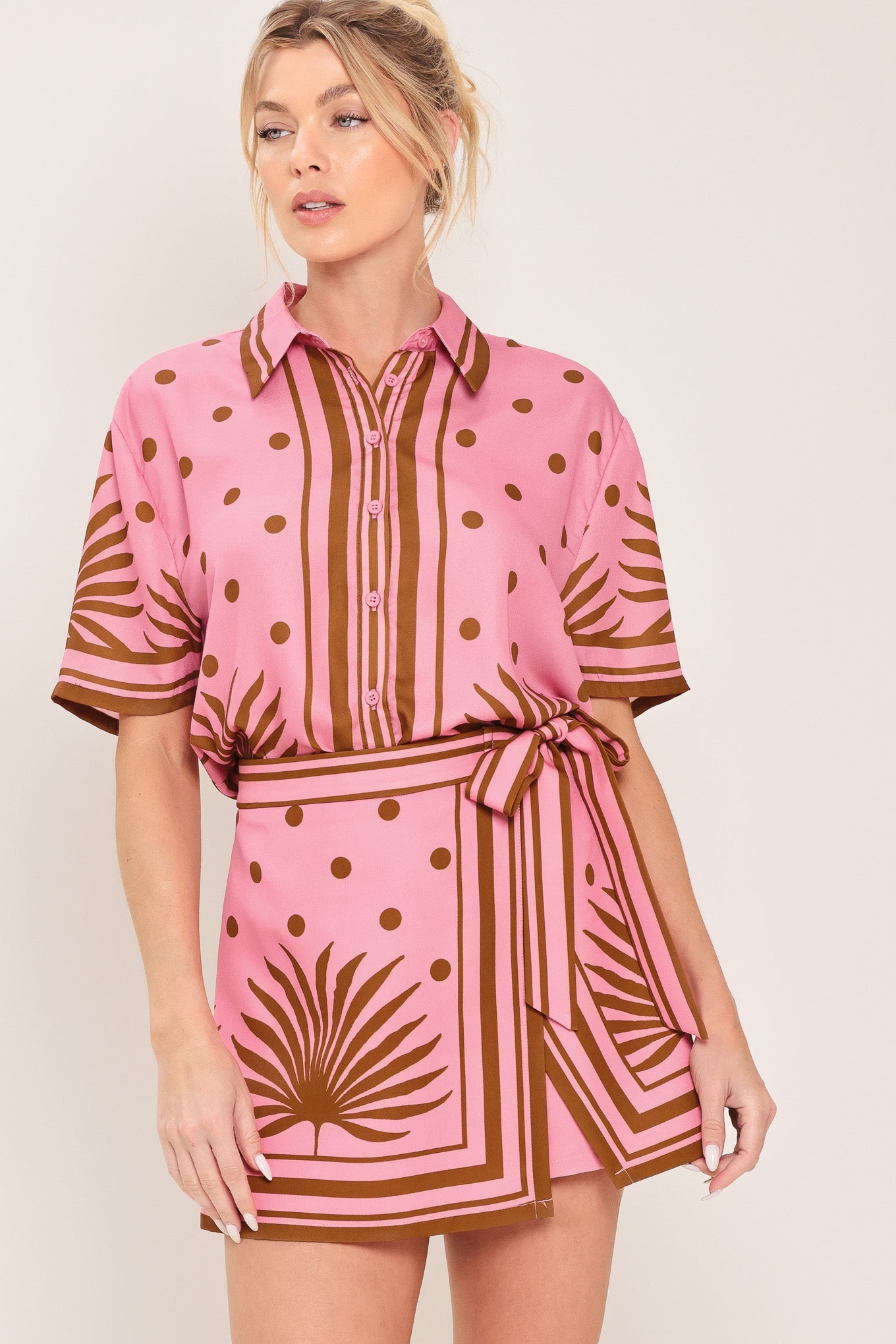 Woman wearing a pink button up top with brown polka dots and printed palms | Flying Tomato