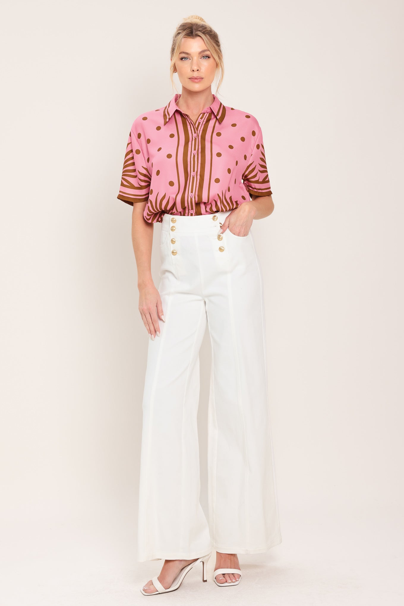Woman wearing a pink button up top with brown polka dots and printed palms | Flying Tomato