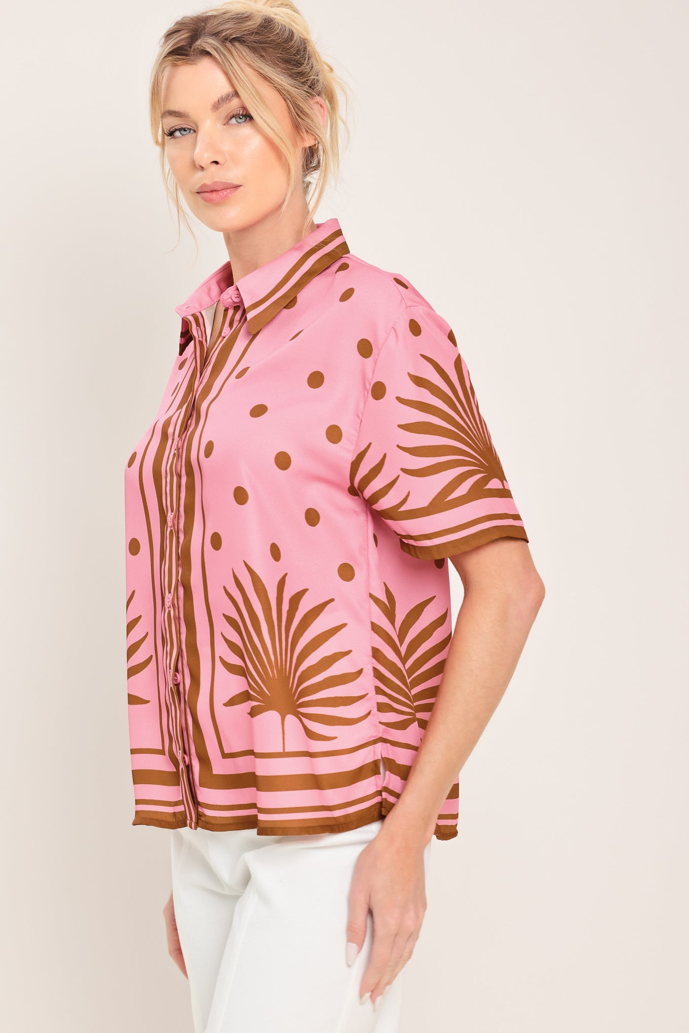 Woman wearing a pink button up top with brown polka dots and printed palms | Flying Tomato