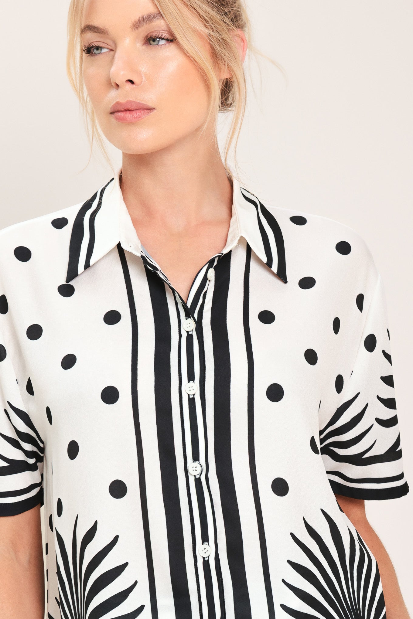 Woman wearing a white button up top with black polka dots and printed palms | Flying Tomato