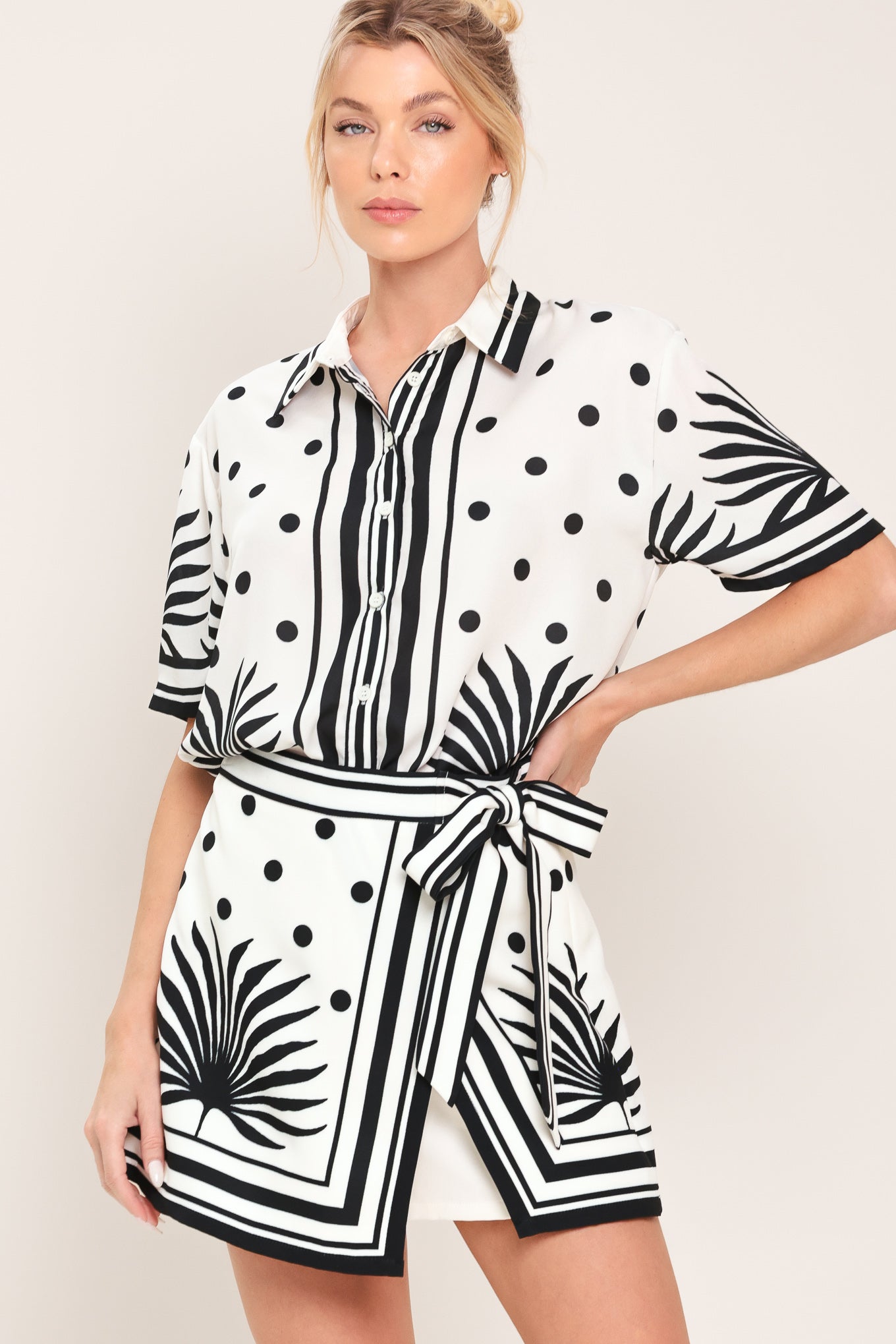 Woman wearing a white button up top with black polka dots and printed palms | Flying Tomato
