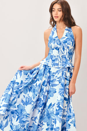 Woman wearing a blue floral top and skirt featuring V halter neckline, corset waist, front tie, peplum and back zipper closure | Flying Tomato