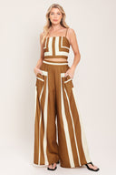 Woman wearing a brown and white geometrical top and pant set featuring crop top with straps and smocked back bodice, wide leg pant with elastic back | Flying Tomato