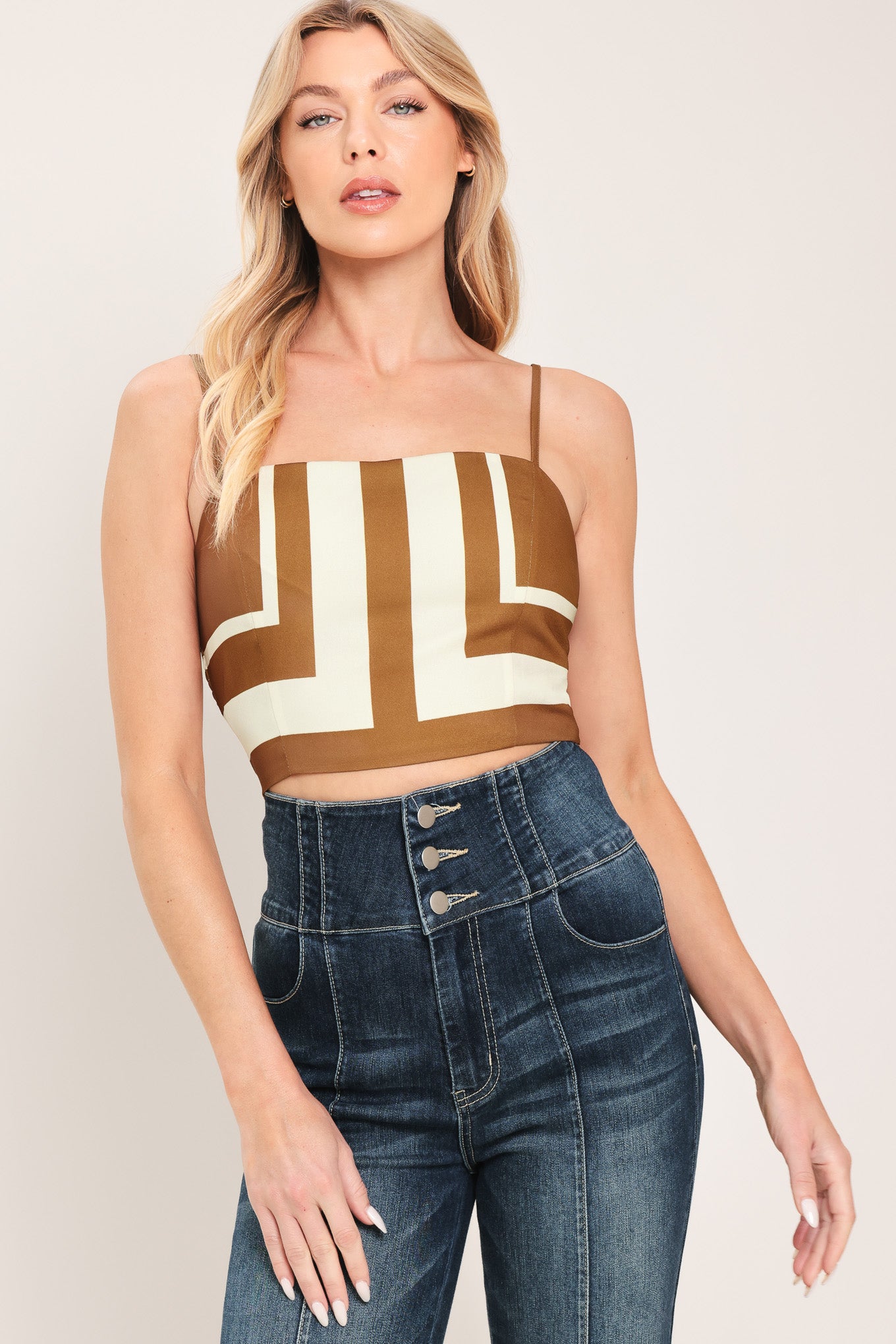 Woman wearing a brown and white geometrical crop top with straps and smocked back bodice | Flying Tomato