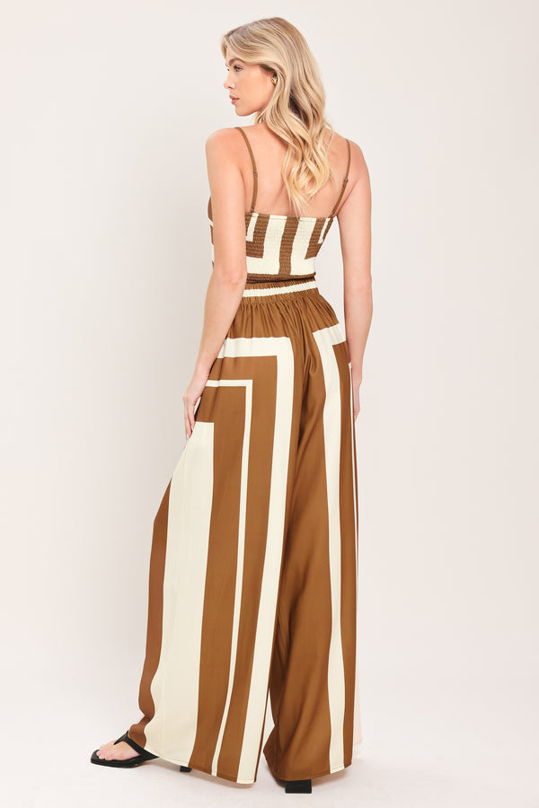 Woman wearing a brown and white geometrical top and pant set featuring crop top with straps and smocked back bodice, wide leg pant with elastic back | Flying Tomato
