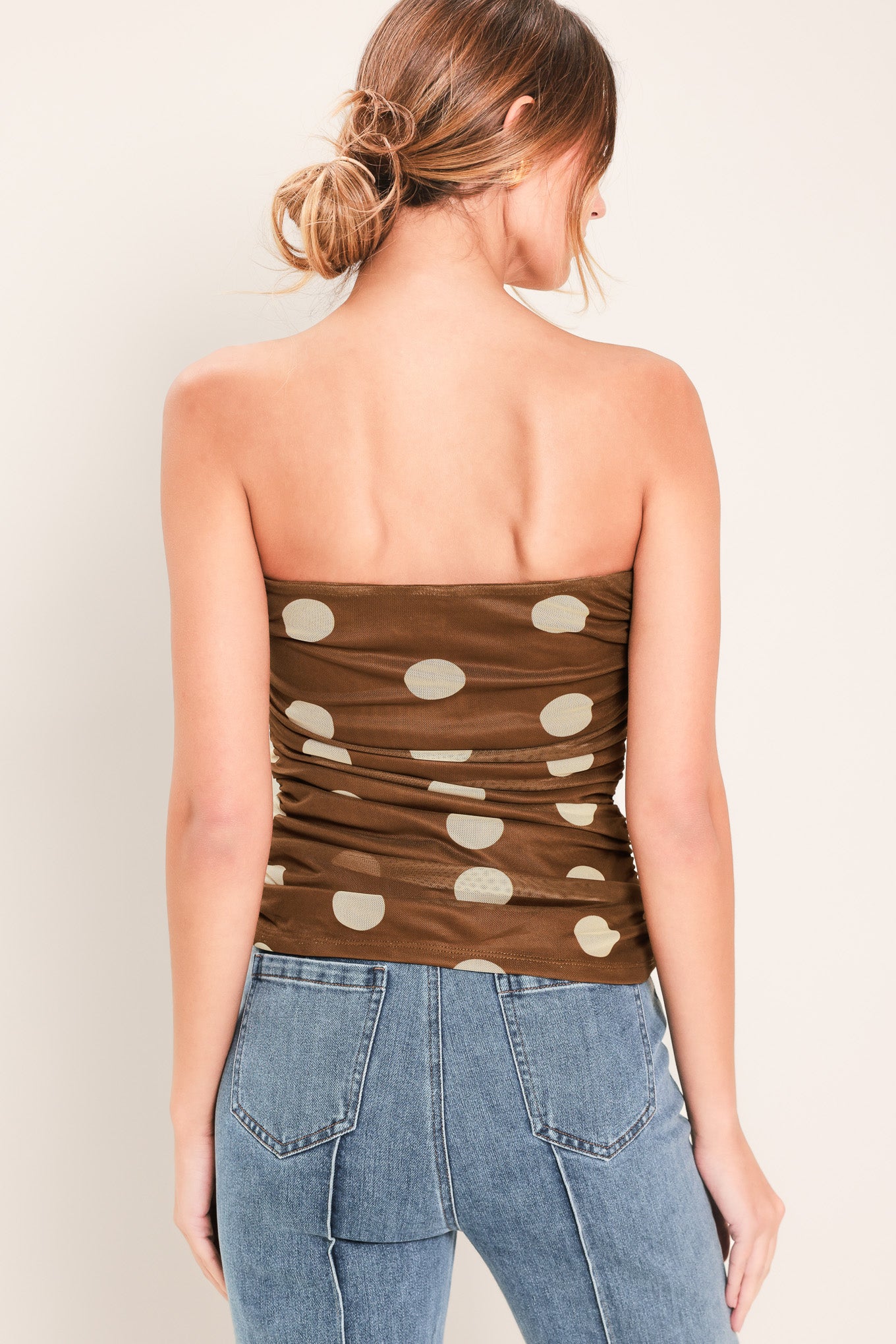 Woman wearing a brown strapless power mesh top with white polka dots and side shirring | Flying Tomato